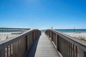 A wooden boardwalk leading to a beach with a clear blue sky. - Summerwind West 804 (Navarre)