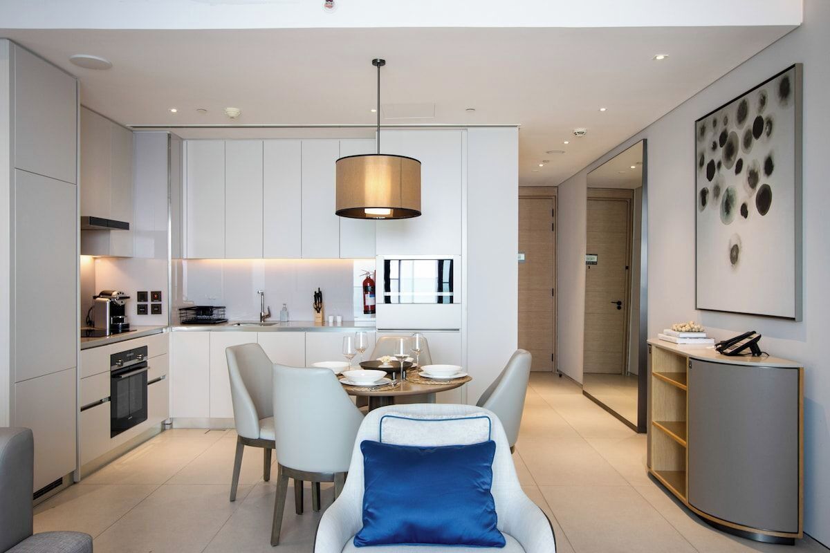 Une cuisine moderne avec des meubles blancs, un coin repas doté d’une table ronde et une décoration minimaliste.