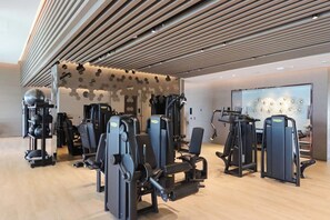 Une salle de sport équipée de divers appareils d’entraînement, notamment des appareils de musculation et des appareils de cardio.