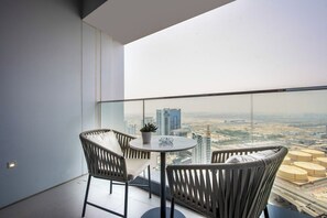 Ein Balkon mit rundem Tisch und zwei Stühlen, mit Blick auf eine Skyline aus Hochhäusern.