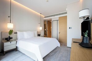 Une chambre d’hôtel moderne avec un grand lit, des lampes de chevet, une table de chevet et un bureau avec une lampe.