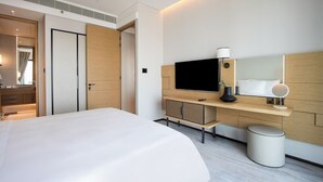 Ein modernes Hotelzimmer mit einem großen Bett, einem Fernseher, einem Schreibtisch mit Computer und einer kleinen Mülltonne.
