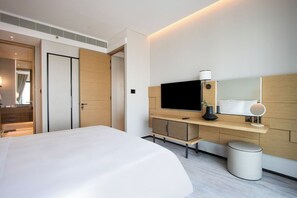 Ein modernes Hotelzimmer mit einem großen Bett, einem Fernseher, einem Schreibtisch mit Computer und einer kleinen Mülltonne.