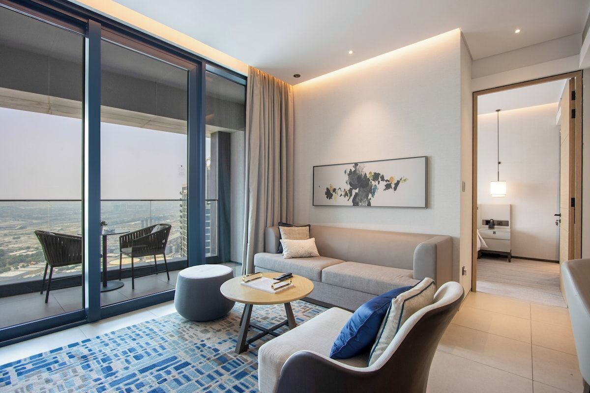 Ein modernes Hotelzimmer mit Balkon, einer Couch, einem Couchtisch und einem Gemälde.