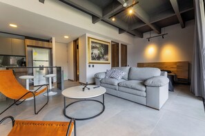 Ein modernes Wohnzimmer mit grauem Sofa, einem runden Couchtisch und einer Wand mit Holzverkleidung.