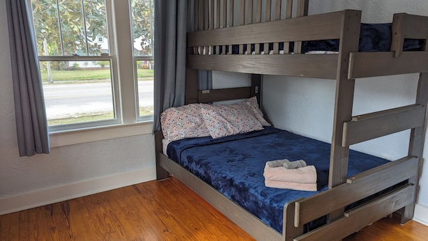 A bunk bed with a blue mattress, a floral pillow, and a towel on the lower bunk. - Charming 2-bedroom 1935 bungalow in downtown New Port Richey (New Port Richey)
