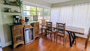 A kitchen with wooden cabinets, a refrigerator, a coffee maker, and a dining table with chairs. - Charming 2-bedroom 1935 bungalow in downtown New Port Richey (New Port Richey)