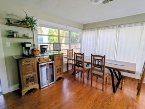 A kitchen with wooden cabinets, a refrigerator, a coffee maker, and a dining table with chairs. - Charming 2-bedroom 1935 bungalow in downtown New Port Richey (New Port Richey)