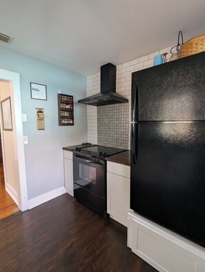 A kitchen with a black refrigerator, a stove, and a tiled backsplash. - Charming 2-bedroom 1935 bungalow in downtown New Port Richey (New Port Richey)