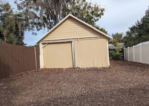 A single-story shed with a gabled roof, surrounded by a wooden fence and mulch ground cover. - Charming 2-bedroom 1935 bungalow in downtown New Port Richey (New Port Richey)