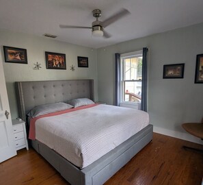 A bedroom with a bed, a nightstand, a chair, and a ceiling fan. - Charming 2-bedroom 1935 bungalow in downtown New Port Richey (New Port Richey)