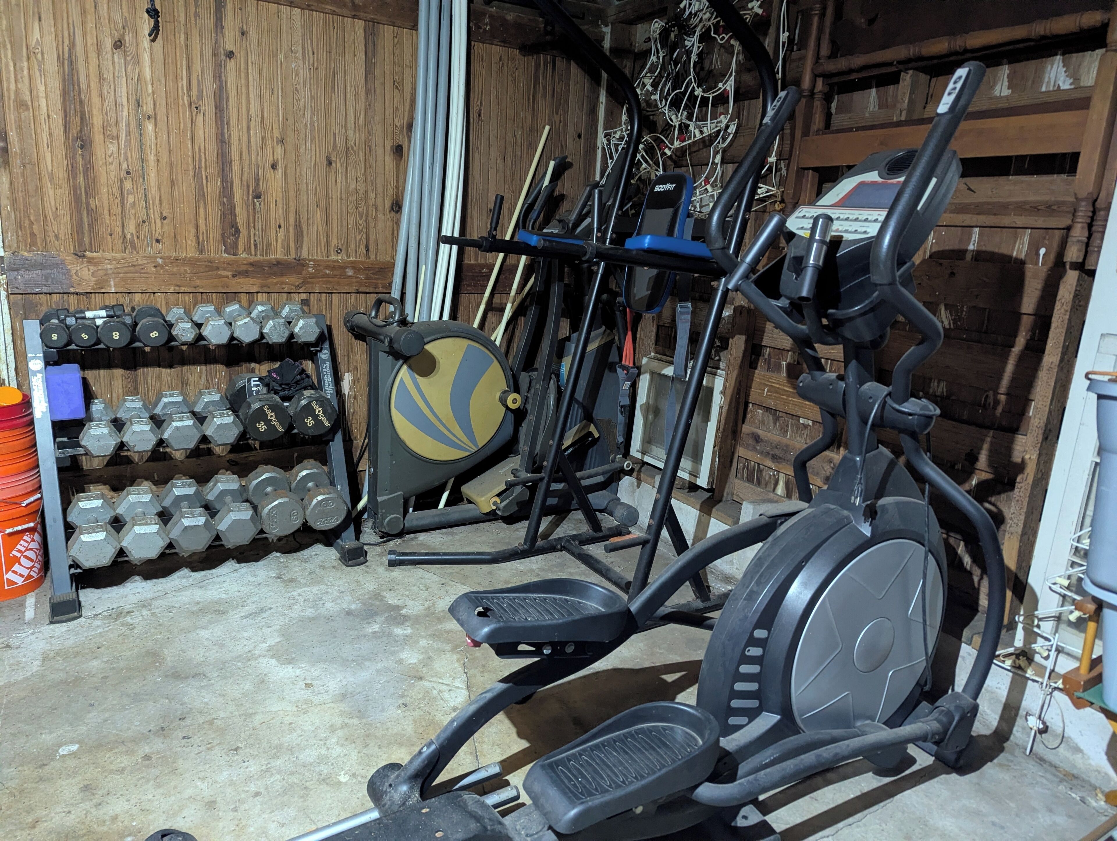A home gym with exercise equipment, including a treadmill, elliptical, and dumbbells.