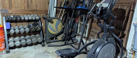A home gym with exercise equipment, including a treadmill, elliptical, and dumbbells.