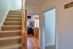A staircase leading to a kitchen area with wooden flooring and a door leading to another room. - Peaceful Lochside Retreat for 4 (Bude)