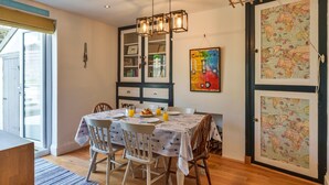A dining area with a table set for two, chairs, a chandelier, and a wall with a map and artwork. - Peaceful Lochside Retreat for 4 (Bude)