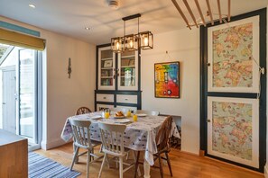 A dining area with a table set for two, chairs, a chandelier, and a wall with a map and artwork. - Peaceful Lochside Retreat for 4 (Bude)