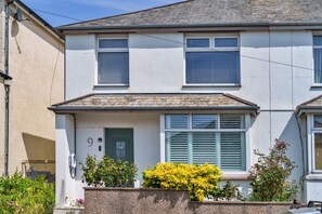 A two-story residential building with a front door, a small porch, and a window with shutters. - Peaceful Lochside Retreat for 4 (Bude)