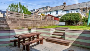 A patio area with a wooden bench and picnic table, surrounded by a low stone wall. - Peaceful Lochside Retreat for 4 (Bude)