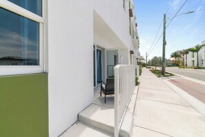 A modern building with a white facade, a visible entrance, and a sidewalk adjacent to the building.