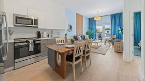 Una cocina moderna con electrodomésticos de acero inoxidable, un comedor con sillas de madera y vistas al exterior.