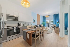 Eine moderne Küche mit Edelstahlgeräten, ein Essbereich mit Holzkästen und Blick ins Freie.