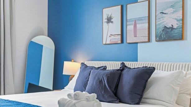 Una habitación de hotel con cama, mesita de noche, lámpara y decoración en la pared.