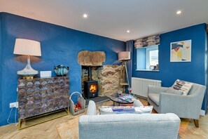 Ein Wohnzimmer mit Kamin aus Stein, einer blauen Wand, einem Fenster mit Blick und einem weißen Sofa.