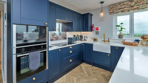 Eine moderne Küche mit blauen Schränken, Edelstahlgeräten und einem großen Fenster mit Blick.