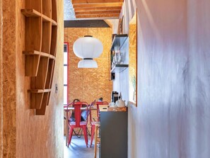 A narrow hallway with wooden walls, a dining area with red chairs, and a hanging light fixture. - Selsey Retreat Near the Beach (Chichester)