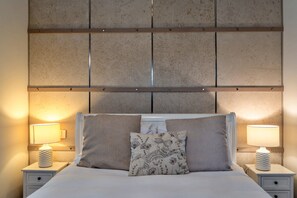 A bed with two pillows, a nightstand with a lamp, and a wall with a textured panel. - Scenic Hot Tub Cottage for 2 (Wimborne)