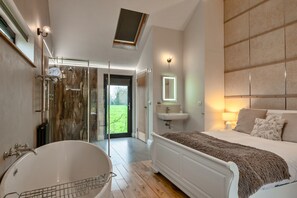 Ein modernes Badezimmer mit einer freistehenden Badewanne, einer in Glas eingefassten Dusche und einem großen Spiegel über dem Waschbecken.