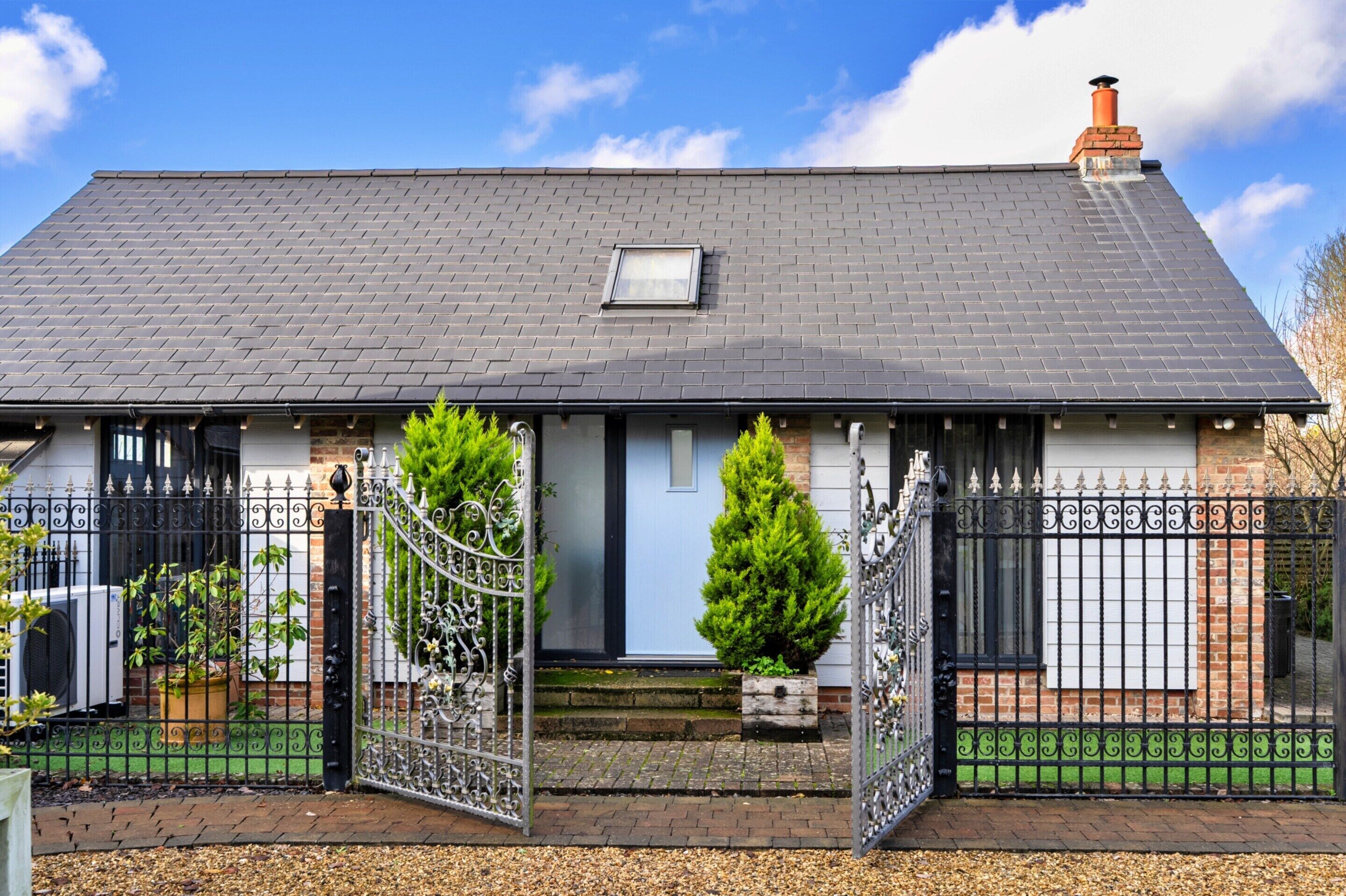 A two-story house with a grey tiled roof, a small dormer window, and a brick chimney.