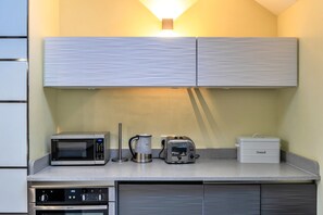 A kitchenette with a microwave, coffee maker, toaster, and bread storage. - Scenic Hot Tub Cottage for 2 (Wimborne)