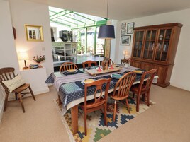 A dining area with a table set for four, surrounded by wooden chairs, a patterned rug, and a cabinet with glass doors.