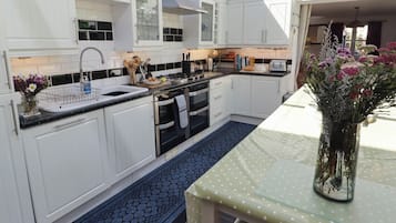Een moderne keuken met witte kasten, een zwart aanrecht en een vloerkleed met blauw patroon.
