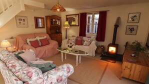 A cozy living room with a sofa, a table, a fireplace, and a staircase. - The Garden Rooms (Narberth)