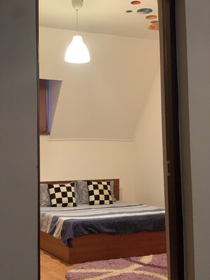 A bedroom with a bed, checkered pillows, a hanging light fixture, and a wall with circular decorations.