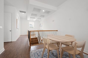 A dining area with a wooden table and chairs, a staircase with a railing, and a view of the outside through a window. - Minions - Arcade - Guest House - Villa - Pool & Spa 7521 (Kissimmee)