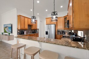 A modern kitchen with granite countertops, stainless steel appliances, wooden cabinets, and pendant lighting. - Minions - Arcade - Guest House - Villa - Pool & Spa 7521 (Kissimmee)