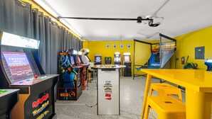 Ein Raum mit Spielautomaten, einem Tischtennis-Tisch und einem gelben Tisch.