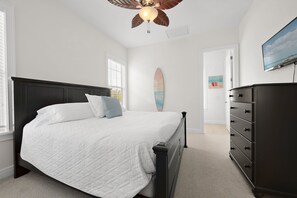 A bedroom with a bed, dresser, ceiling fan, and a surfboard on the wall. - Minions - Arcade - Guest House - Villa - Pool & Spa 7521 (Kissimmee)