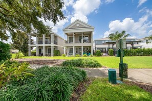 A two-story building with a balcony, surrounded by well-maintained landscaping and a clear sky. - Minions - Arcade - Guest House - Villa - Pool & Spa 7521 (Kissimmee)