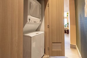 A laundry room with a washing machine and dryer, wooden doors, and a hallway leading to a dining area. - Moderno y Acogedor/Capcana/1Br+1Mezzanine (Punta Cana)