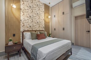 Une chambre moderne équipée d’un lit, de tables de chevet, d’une armoire et d’un appareil de climatisation.