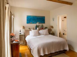 Un dormitorio con una cama grande, un cuadro en la pared y piso de madera.