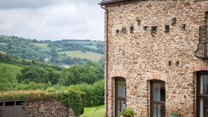 A stone building with a view of green hills. - Retreat With Valley-view Deck (Ilfracombe)