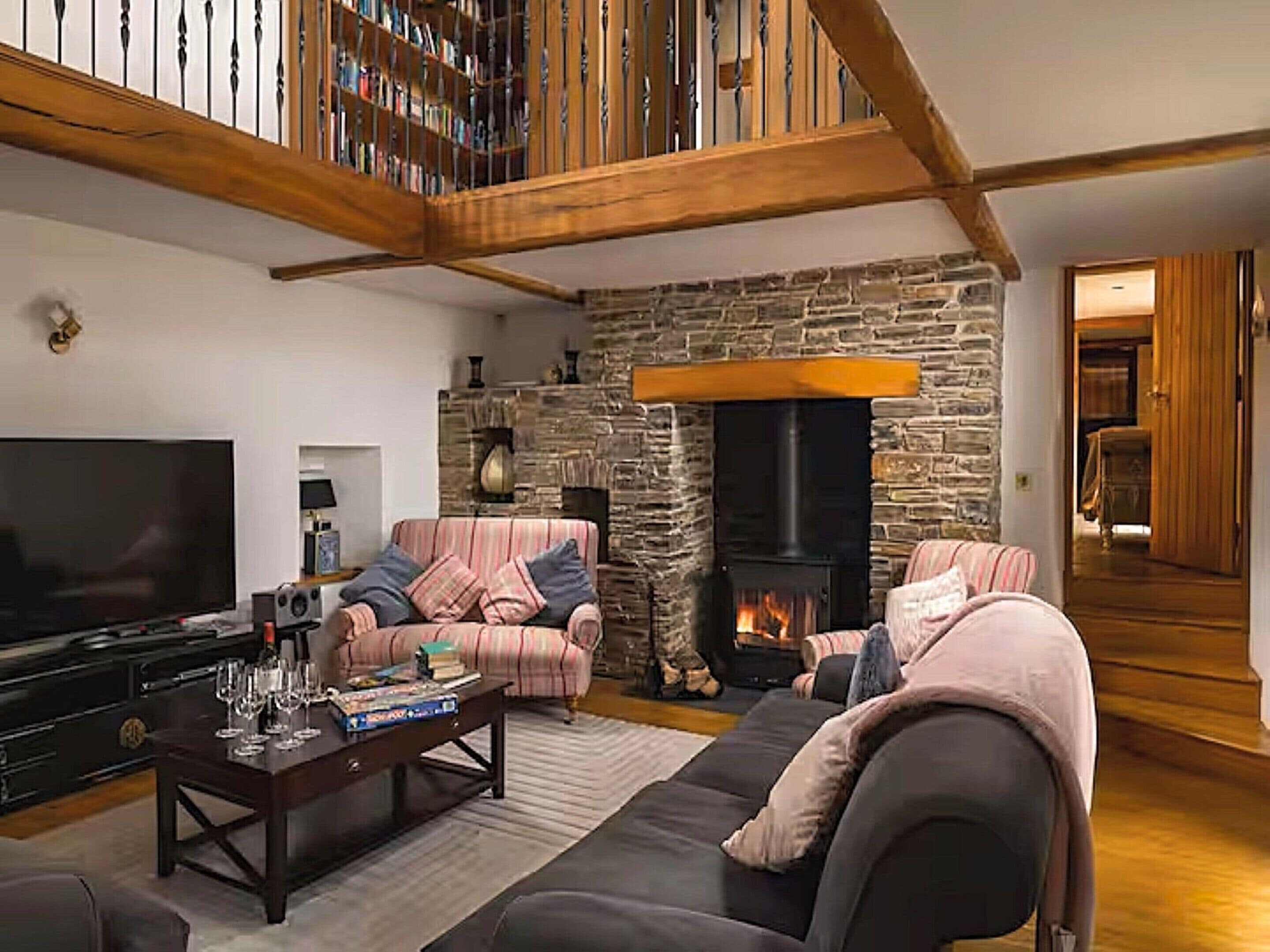 Un salon chaleureux avec une cheminée en pierre, un téléviseur à écran plat et des sièges confortables.