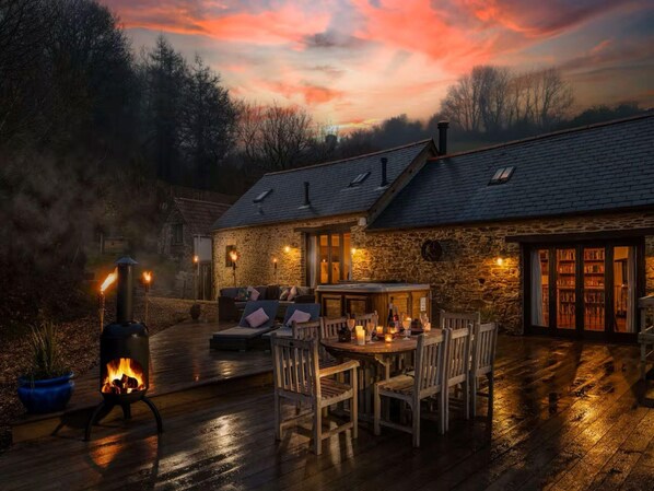 A stone building with a fireplace, outdoor seating, and a view of the sky. - Retreat With Valley-view Deck (Ilfracombe)