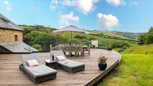 A deck with outdoor furniture, a table set for dining, and a scenic view of hills. - Retreat With Valley-view Deck (Ilfracombe)