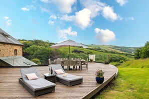 Eine Terrasse mit Gartenmöbeln, einem Esstisch und einem herrlichen Blick auf die Hügel.